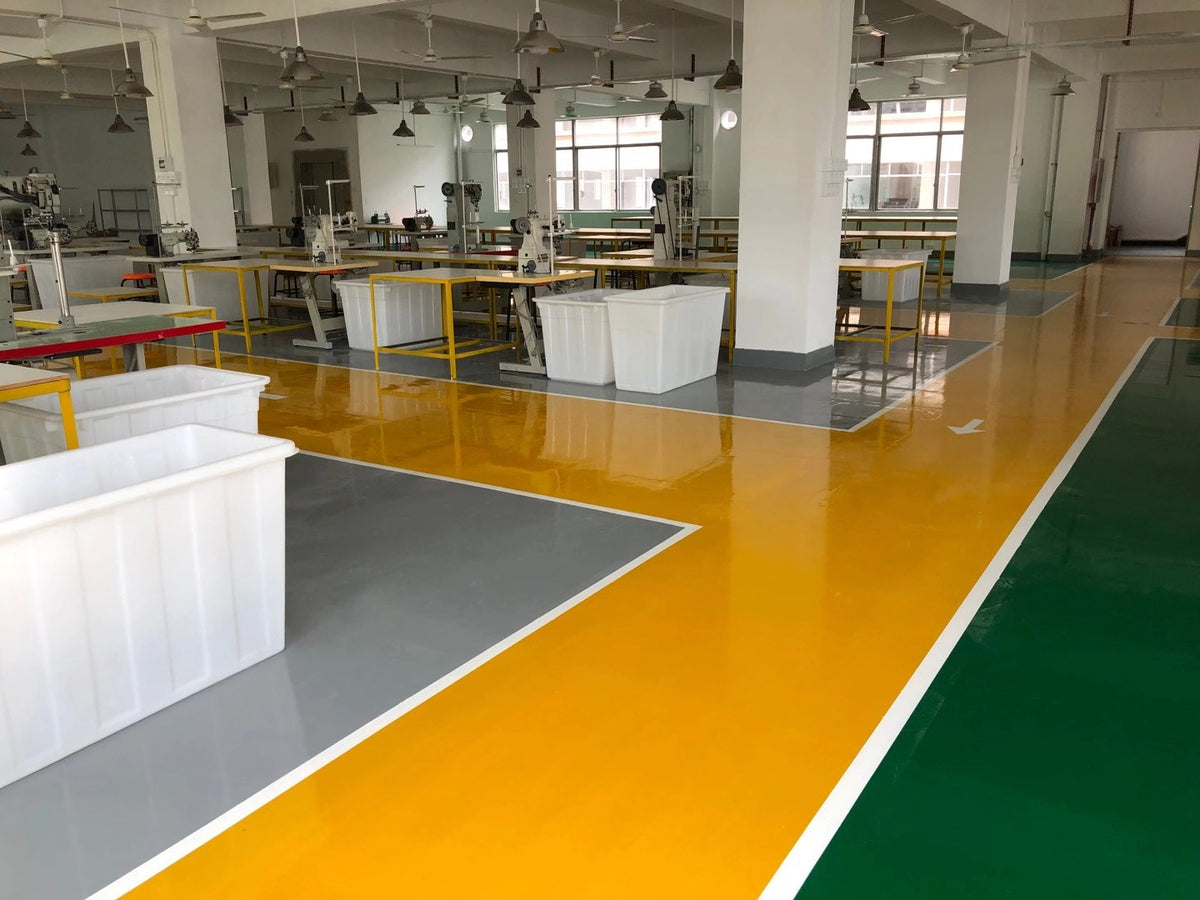 White component bins beside sewing workstations and a marked factory aisle.