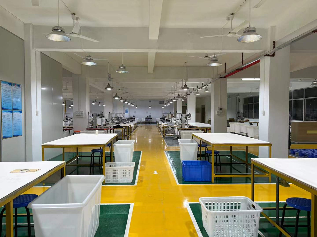 Preparation tables and component bins arranged along a central yellow workshop aisle.