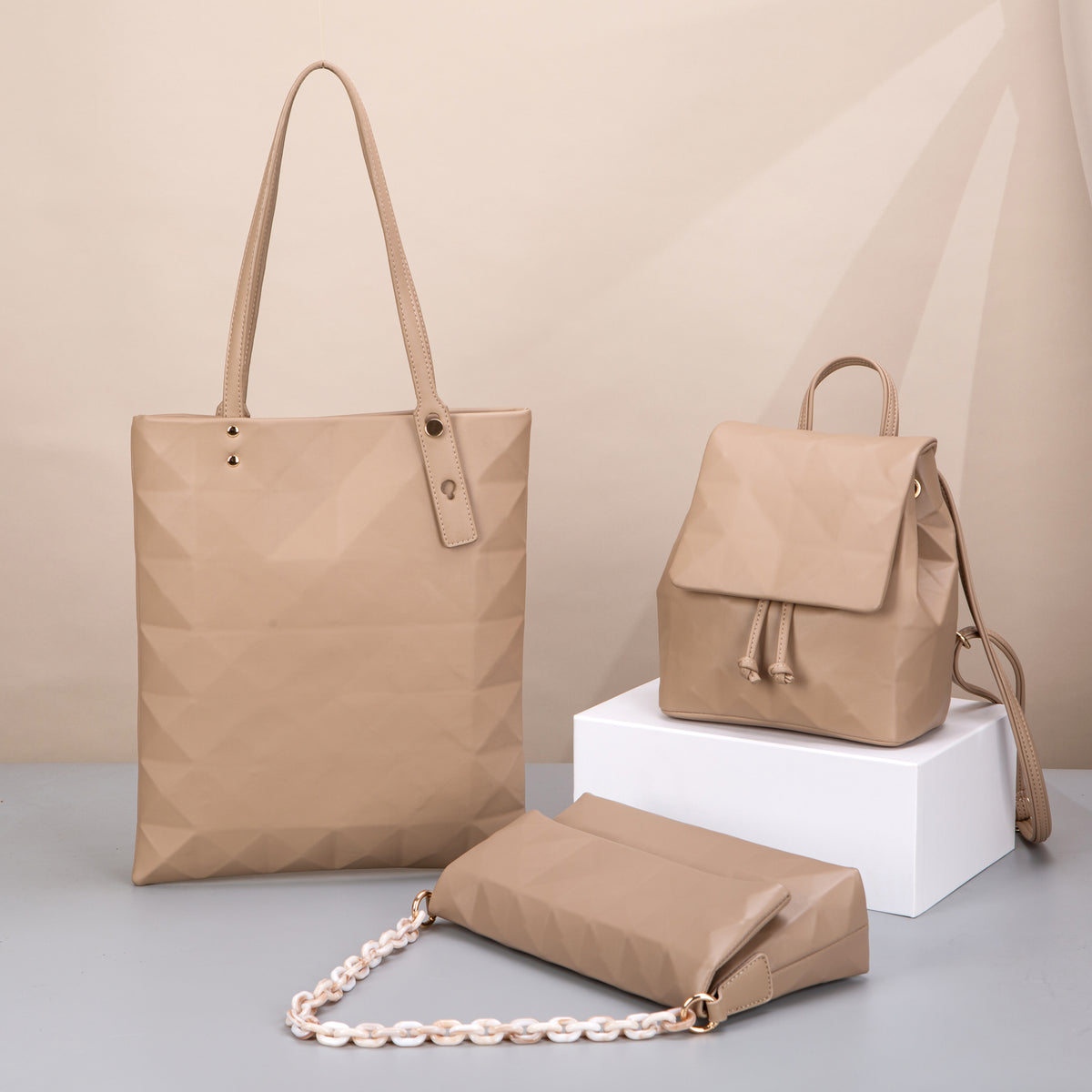Beige faceted tote, drawstring backpack and chain-strap shoulder bag