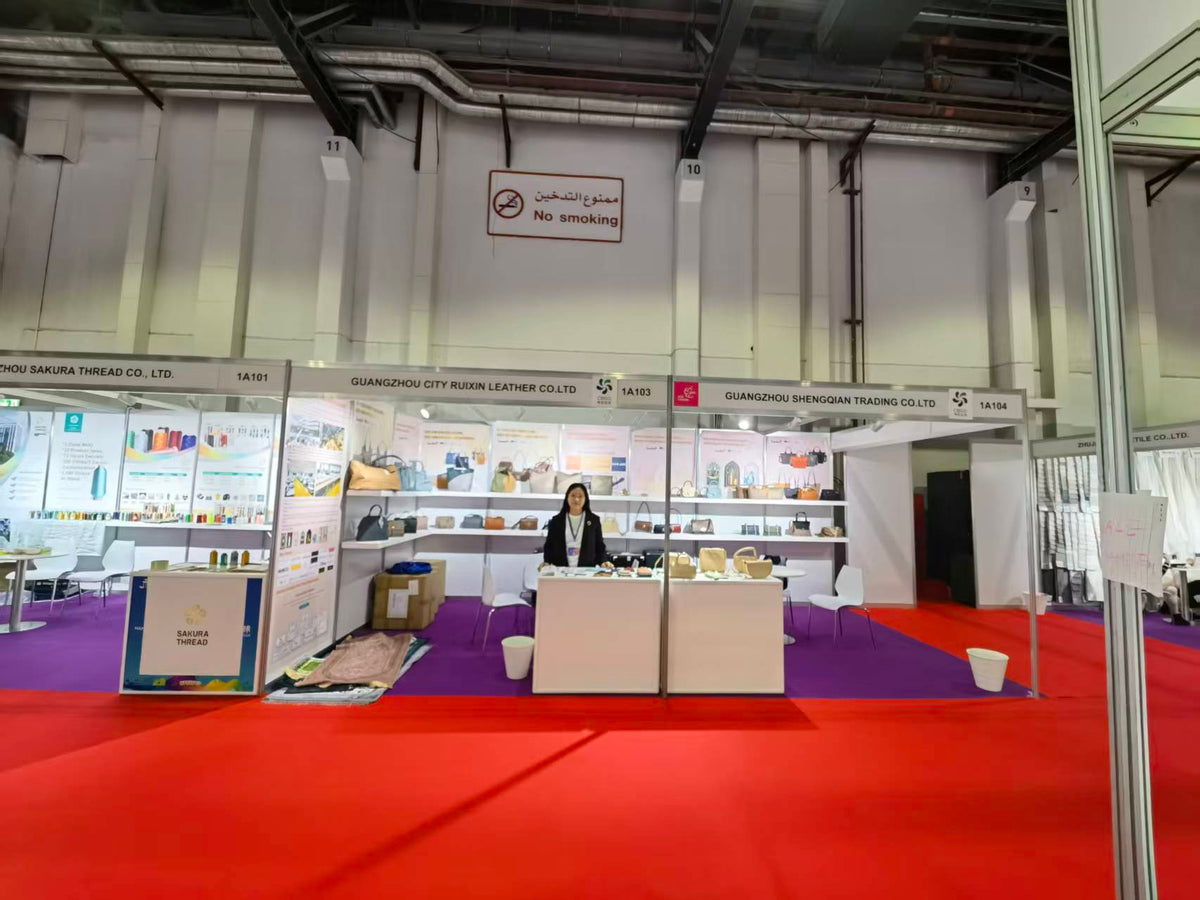 Wide view of exhibition booths displaying handbag samples and accessories.
