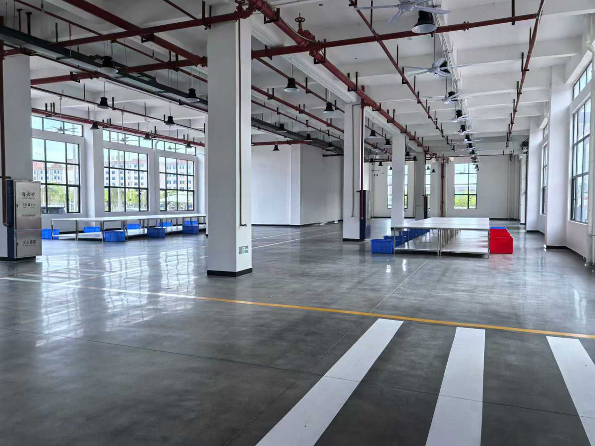 Open preparation floor with long worktables, blue bins and marked pedestrian routes.
