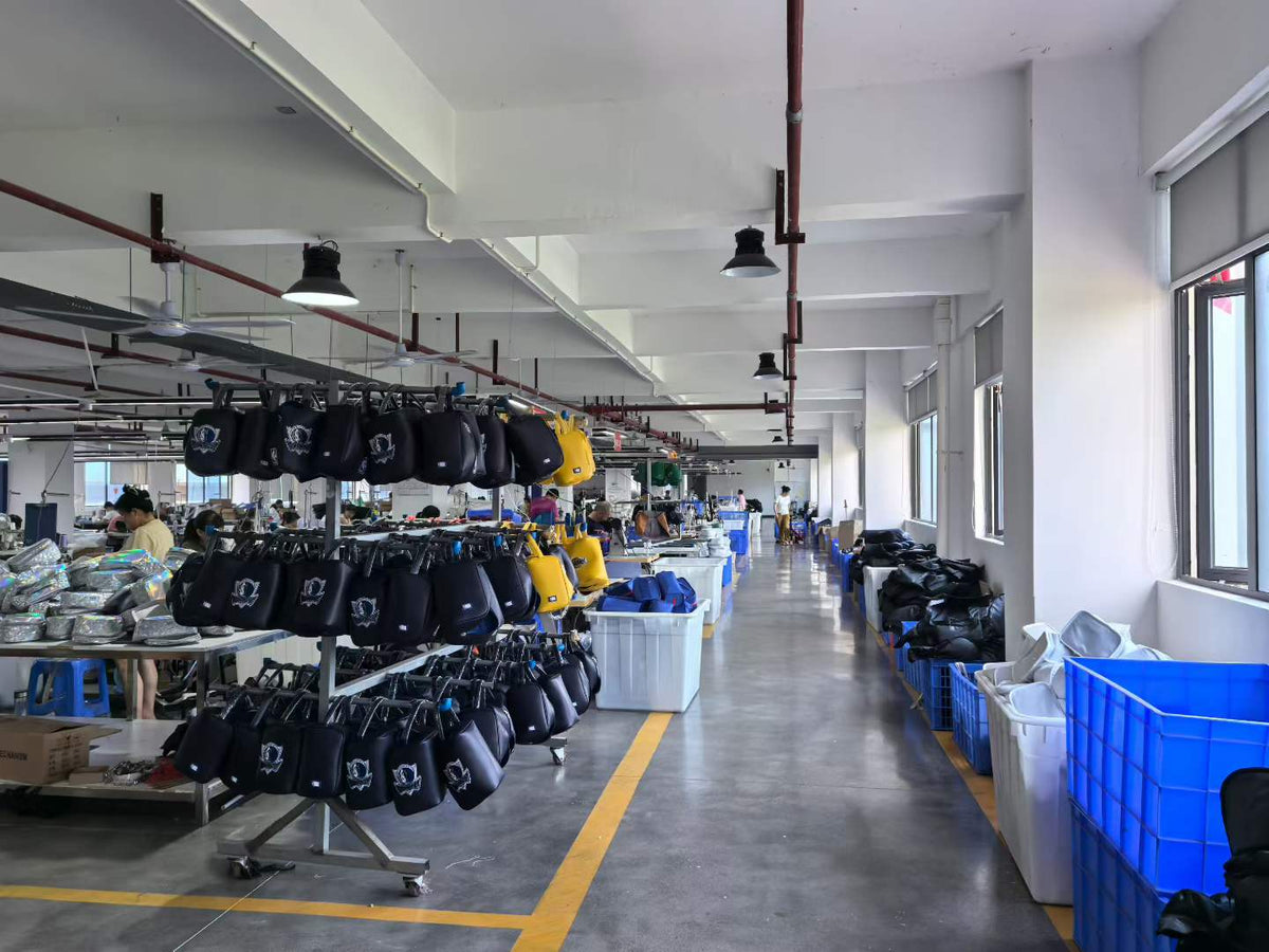 Racks of dark handbags and yellow bags beside sewing workstations and component bins.