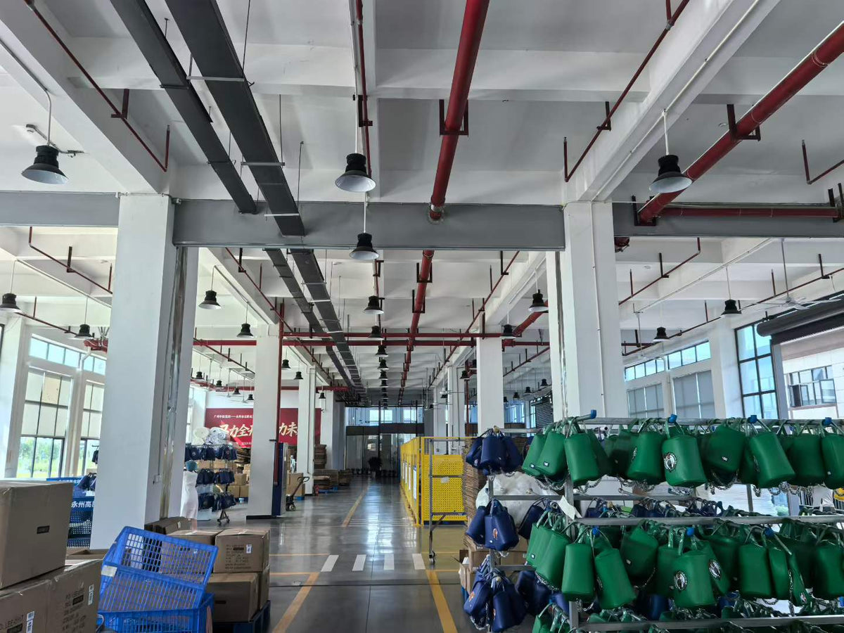 Green and blue handbags arranged on rolling racks beside the workshop aisle.