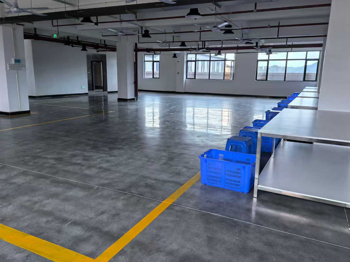 White preparation tables with blue baskets beside a marked factory walkway.