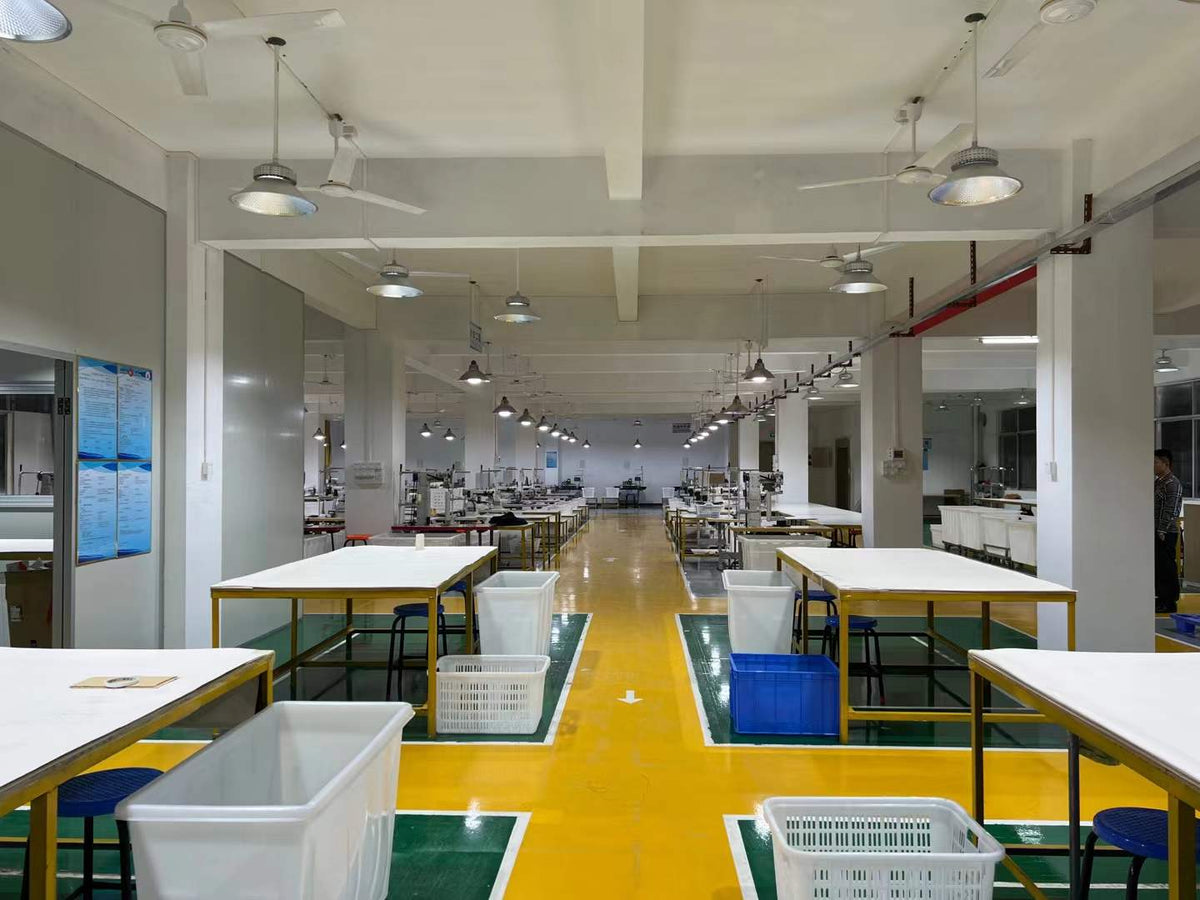 Wide view of preparation tables, sewing stations and material bins in the workshop.