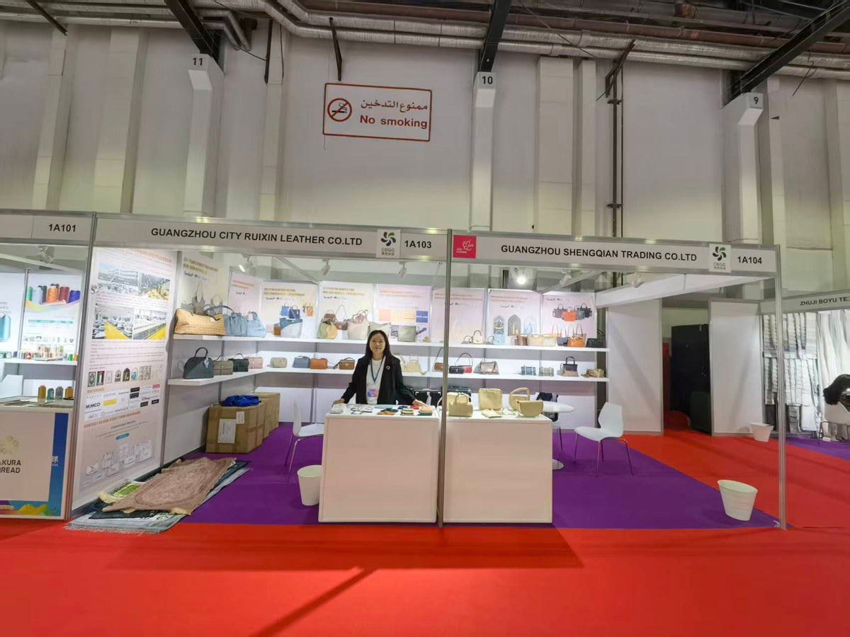 Handbag exhibition booth with display counters and a visitor seating area.