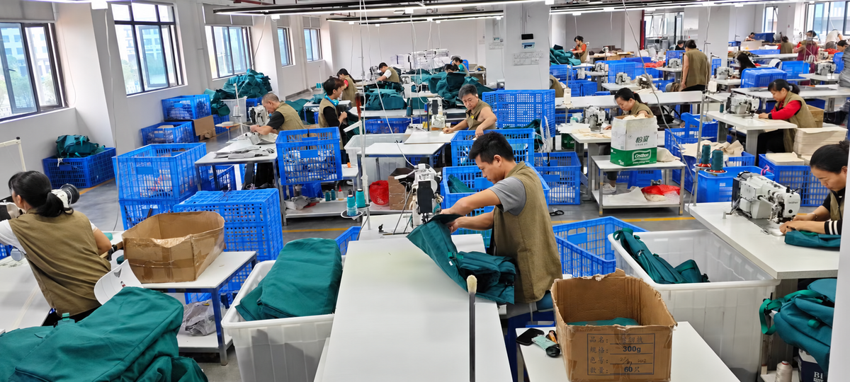 Bag sewing and assembly workshop with workers, sewing machines and teal bag components