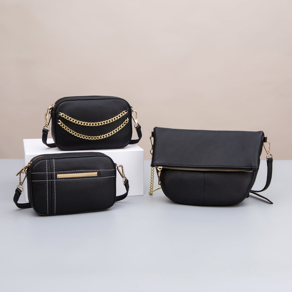 Three black textured crossbody bags with chain, stitch and zip details