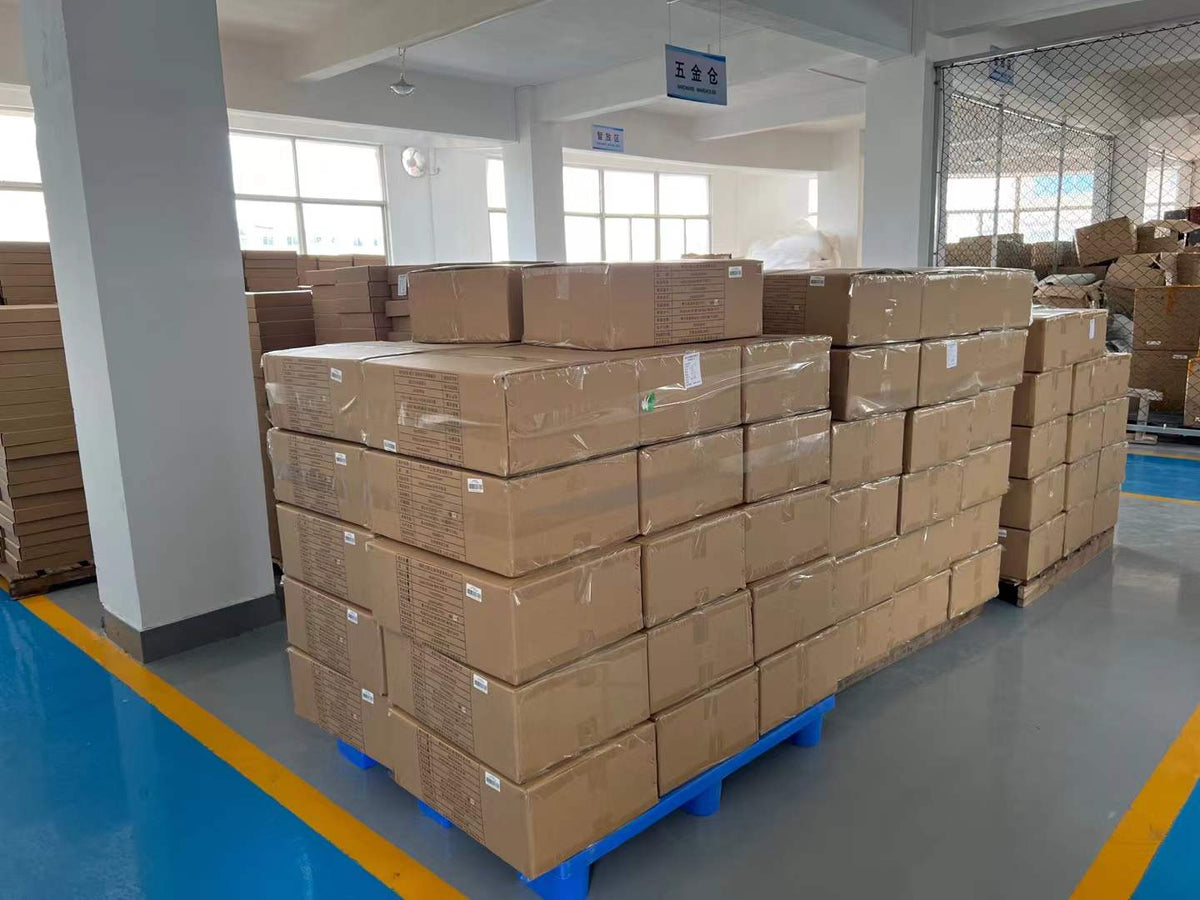 Sealed cartons stacked on pallets beside marked factory storage aisles.