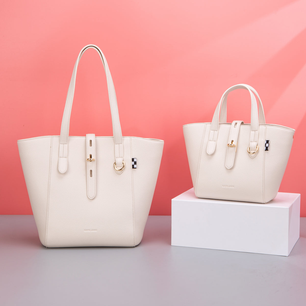Two cream textured totes with different handle lengths and buckle tabs