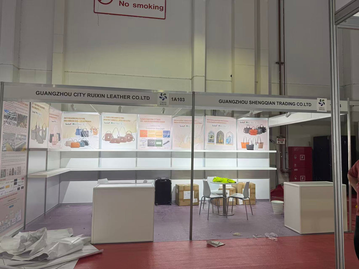 Exhibition booth being prepared with empty display shelves and handbag posters.