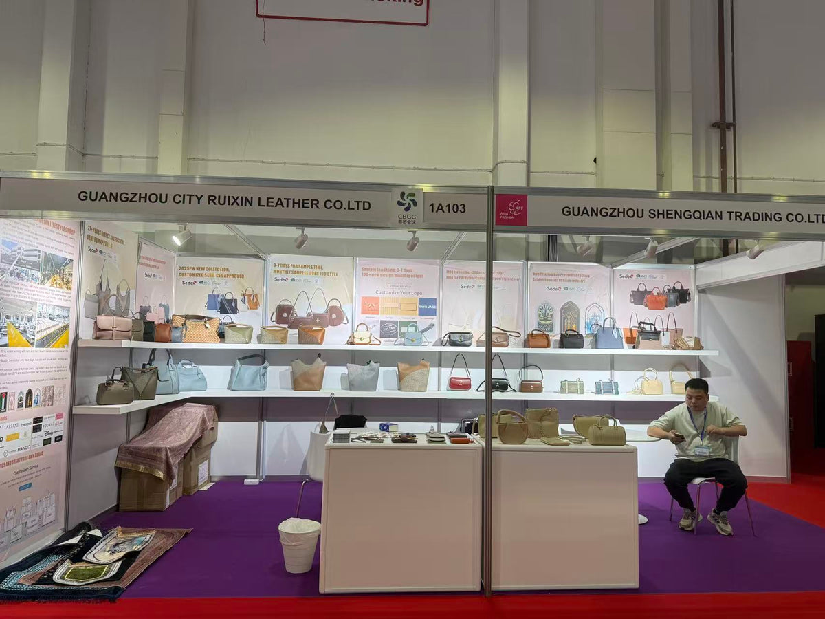 Handbag samples displayed on white shelves with accessory counters in an exhibition booth.