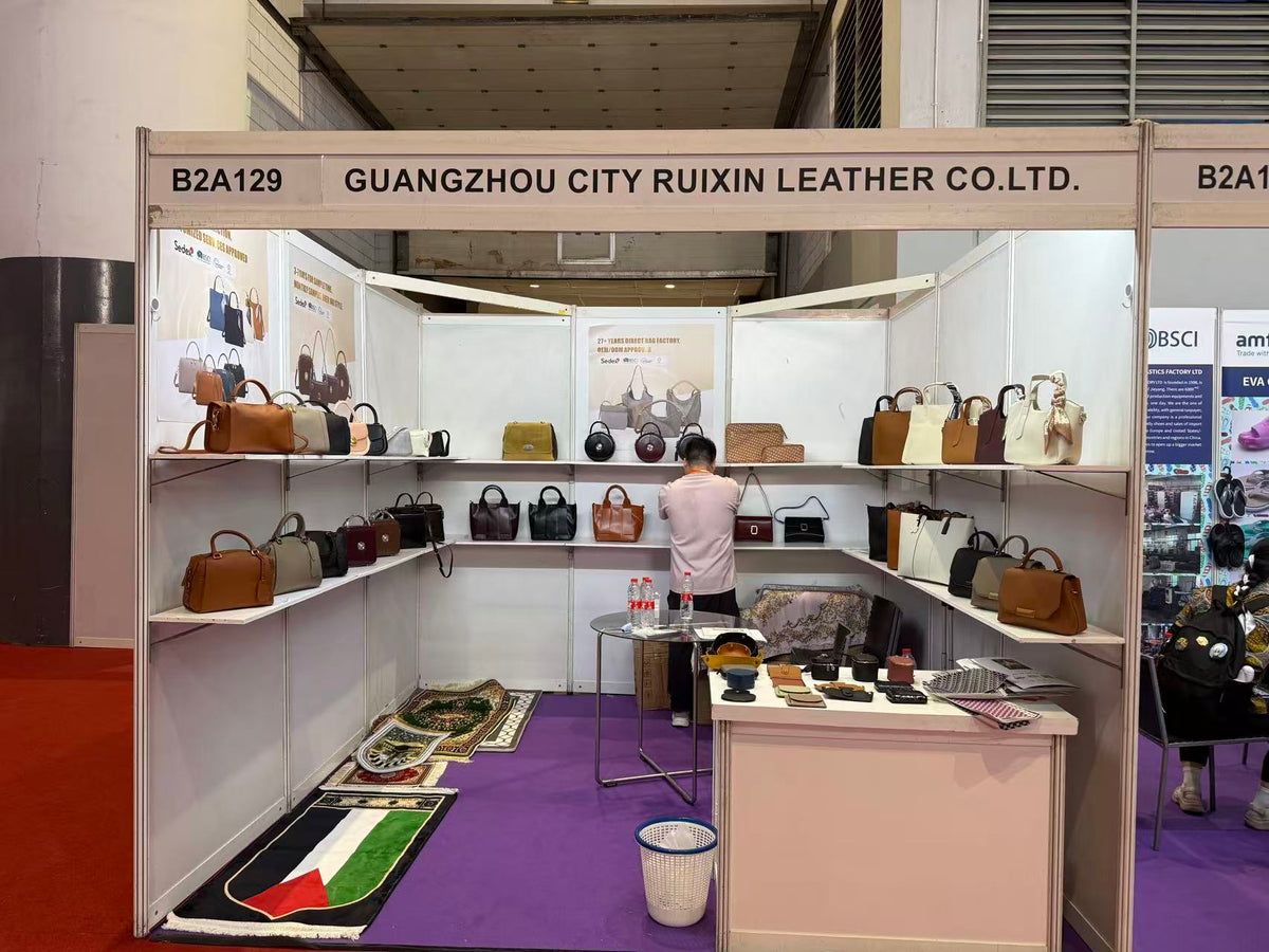 Handbags displayed on three walls of a trade exhibition booth with a sample counter in front.