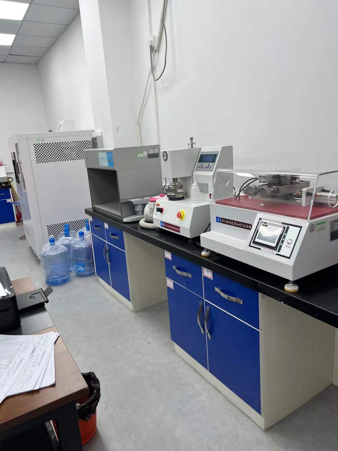 Bench-mounted testing equipment arranged along cabinets inside the factory testing room.