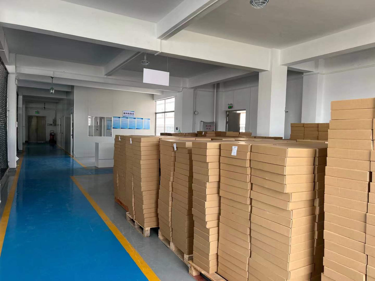 Stacks of flat cartons stored beside a marked aisle and incoming inspection area.
