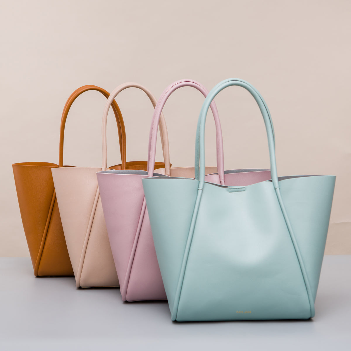 Four open-top totes with slim long handles in tan, blush, pink and pale blue