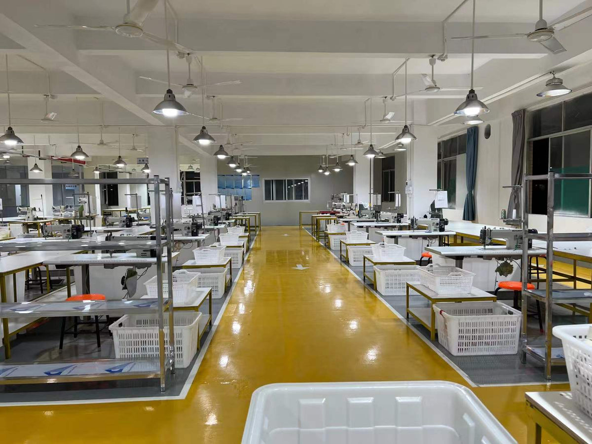 Sewing machines and white component baskets arranged along a marked production aisle.