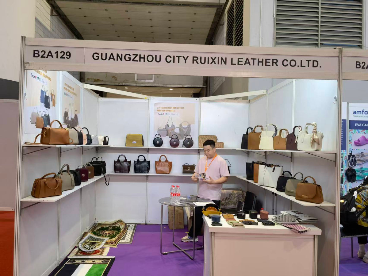 A person reviewing materials inside a booth displaying top-handle bags and totes.
